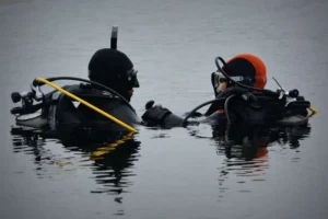 Persona principiante preparándose para bucear con apoyo de un instructor en aguas tranquilas