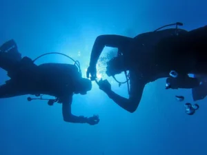 Persona principiante preparándose para un bautismo de buceo con instructor en aguas tranquilas