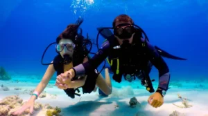 Instructor llevando de la mano a una buceadora durante un bautismo de buceo para principiantes