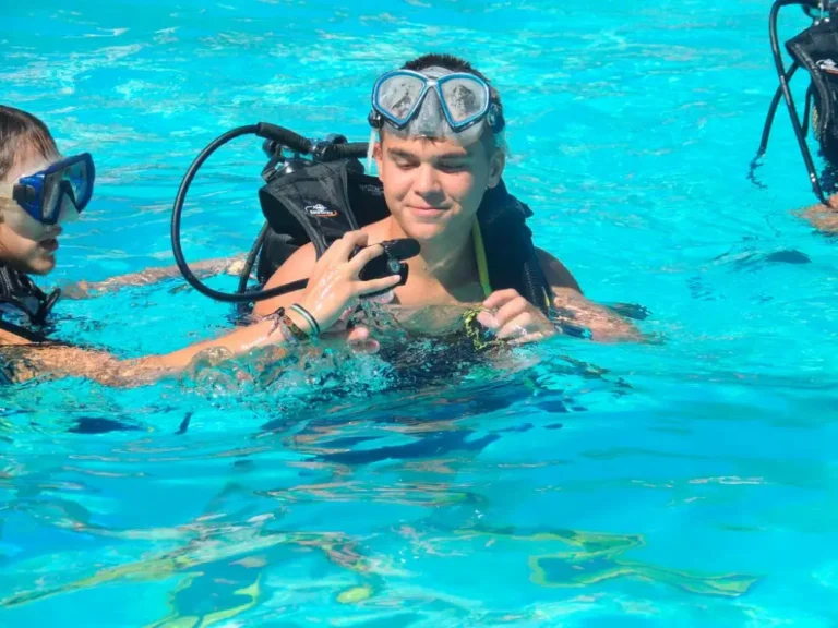 Niño aprendiendo con instructor durante un bautismo de buceo para principiantes