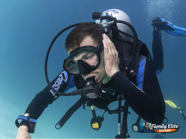 Diver in the water with a hand on the ear during a scuba dive