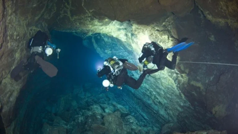 Three divers exploring a volcanic cave underwater in Lanzarote