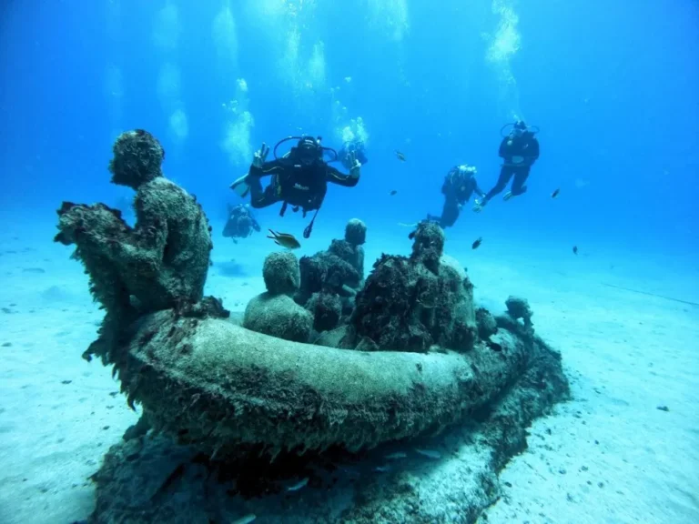 Group of divers next to the zodiac statue with people at the Atlantic Museum