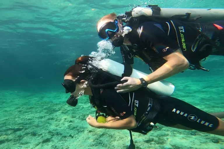 Instructor helping a beginner female diver during a scuba diving experience