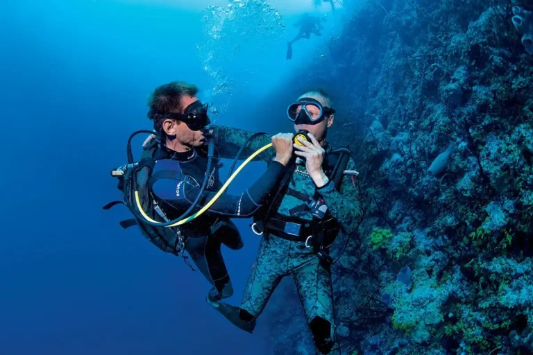 Dive master ayudando a un buceador con el regulador de emergencia durante una práctica de seguridad