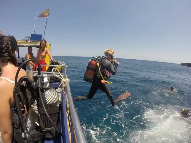 Instructor helping a diver on a boat before starting a scuba dive in the Canary Islands